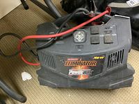 Front view of black MotoMaster Eliminator 700W Power Pack showing decal and cables attached.