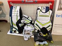 Clear shot of the full kids road hockey set including mini net, goalie protective gear, helmet, and rollerblades.
