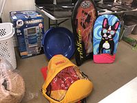 Wide view showing all sleds including the Pelican sled with cover, Air Thunder snow boogie, two styrofoam boards and two round saucer sleds.