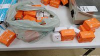 Lot showing 19 Sonoff S31 Lite ZigBee Smart Plugs in orange boxes; some boxes empty; plugs visible in and around bags.