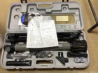 Complete telescope kit in molded carrying case showing telescope tube on tripod and accessories, instruction manual