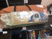 Photo of orange carrying bag with Terra-Gear 18x10 Pentagon Dome Tent label and tent image visible through plastic window.