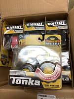 Six packaged Tonka Monster Metal Movers toy trucks in a box, showing fronts of packages with Tonka branding and clear plastic displaying the trucks.