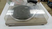 Turntable with closed dust cover, showing Pioneer logo and power cable on top.