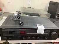 Front angle view of Yamaha RX-330 stereo receiver with visible power cord, placed on white table surface.