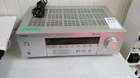 Front angled view of silver Yamaha receiver showing ventilation slots, control buttons, and large volume knob.