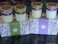 Four naturally scented candles in two gift boxes, each candle 7.4 oz, showing packaging and jars.