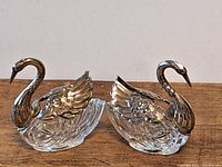 Pair of swan figurines side view with wings closed showing their shape and silver accents.