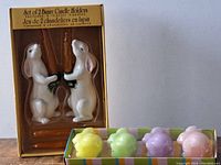Boxed set of two ceramic white bunny candle holders holding carrot candles and a box of four pastel bunny candles.