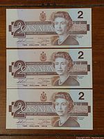 Front view of three 1986 Canadian two dollar bills showing Queen Elizabeth II portrait and denominations