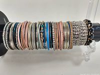 Photo of over 60 assorted costume jewelry bracelets arranged on a display stand showcasing various styles and finishes