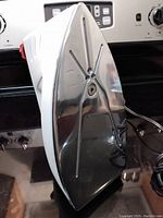 Side view showing the metal soleplate with cross grooves and steam holes.