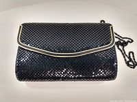 Front view of the black evening purse showing scale-like textured exterior and metal chain strap.
