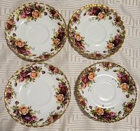 Four Royal Albert Old Country Roses bone china saucers shown from the top, illustrating the floral pattern and gold trim.