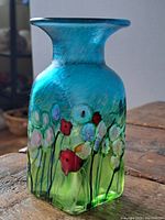 Full view of the square base shaped art glass vase with a gradient of blue and green colors and floral pattern.