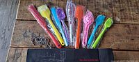 Photo showing multi-colored silicone spatulas and kitchen utensils along with metal hooks and box.