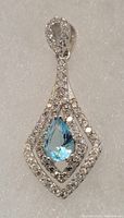 Front view of the sterling silver pendant showing the pear-shaped blue topaz surrounded by white topaz stones.