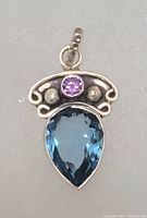 Front view of sterling silver pendant with blue tanzanite pear-shaped stone and small round purple amethyst with silver bead accents.
