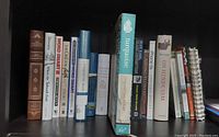 Books arranged upright showing titles spanning various topics including language, cooking, natural history, religion, and more.