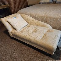 Chaise lounge chair angled showing upholstery, pillow, and legs.