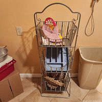 Front view of the metal basket tower showing 3 removable wire baskets, each basket containing miscellaneous household items.