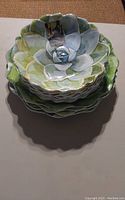 Stack of plastic bowls shaped like succulent leaves with green and white gradient colors
