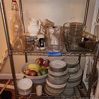 Shelving unit with assorted kitchen tableware and accessories grouped by type