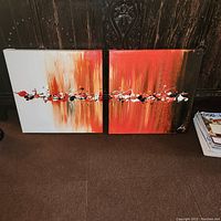 Two side-by-side abstract paintings against a dark wood background showing dominant red, black, and white colors