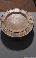 Single wooden charger plate with Roman numerals around the rim.