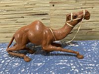 Full side view of the camel figurine showing the camel laying down with legs bent and visible reins.