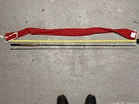 Full length view of Fernwick Woodstream two-piece fly fishing rod alongside yellow measuring tape showing length to be about 8.5 feet. Included red cloth protective sleeve shown.