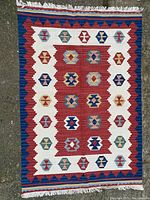 Full view of the hand woven Kilim rug laid flat on the ground showing the full pattern and fringe details.