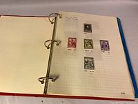 Photo of first page in the album showing five assorted vintage postage stamps with handwritten notes and values.