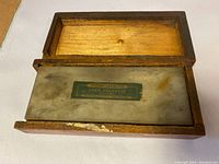 Norton Abrasives Hard Arkansas oilstone in its wooden box with the lid open, showing the stone with label.