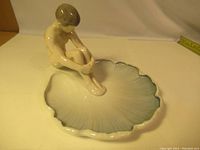 Overall view of the Royal Copenhagen ceramic sculpture showing the nude sitting figure on shell-shaped base.