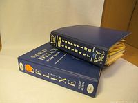 Two blue stamp collector albums stacked, showing front and spine of World Deluxe and BMK albums