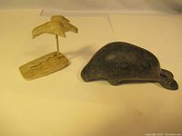 Two Inuit carvings displayed side by side on plain background, showing size and color contrast.
