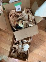 Two cardboard boxes filled with ceramic items wrapped in brown paper, focusing on the Tony Wood Toby jug.