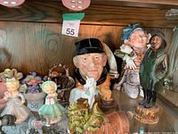 Shelf display of various Japan and Royal Dalton ceramic figurines including small girls, animals, and characters.