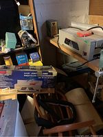 Tool on wooden shelf next to original box and miscellaneous items