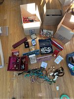 Overhead view of open cardboard boxes and assorted jewelry on hardwood floor