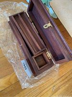 Top view of open wooden jewelry box showing removable tray and compartments inside.