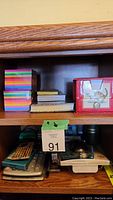 Sticky notes, notepads, and red metal cash box on wooden shelf