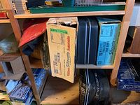 Shelving with brown and black Samsonite Silhouette suitcase sets in original cardboard boxes, and an American Tourister soft suitcase beneath.