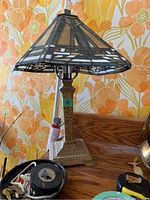 Full view of Tiffany style stained glass table lamp on wooden surface against floral background