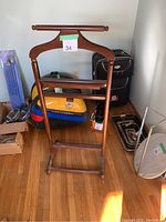 Photo of vintage wooden suit stand showing front view with hanger and base, marked with green tape number 34
