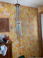 Full view of wind chime hanging against floral wallpaper