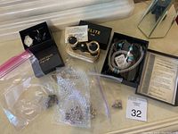 Wide-angle photo showing spread of costume jewelry items including jewelry boxes, opera glasses, and certificate of quality assurance.