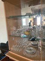 Glass cabinet filled with crystal glassware including stemmed glasses, small bowls, and plates