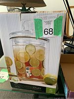 Photo of boxed Aruba beverage dispenser showing glass container with dome lid and silver spigot, with lime slice decoration on the box.